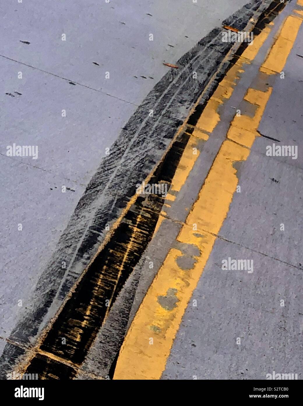 Heavy, panicked skid marks veer across a double yellow line. Stock Photo