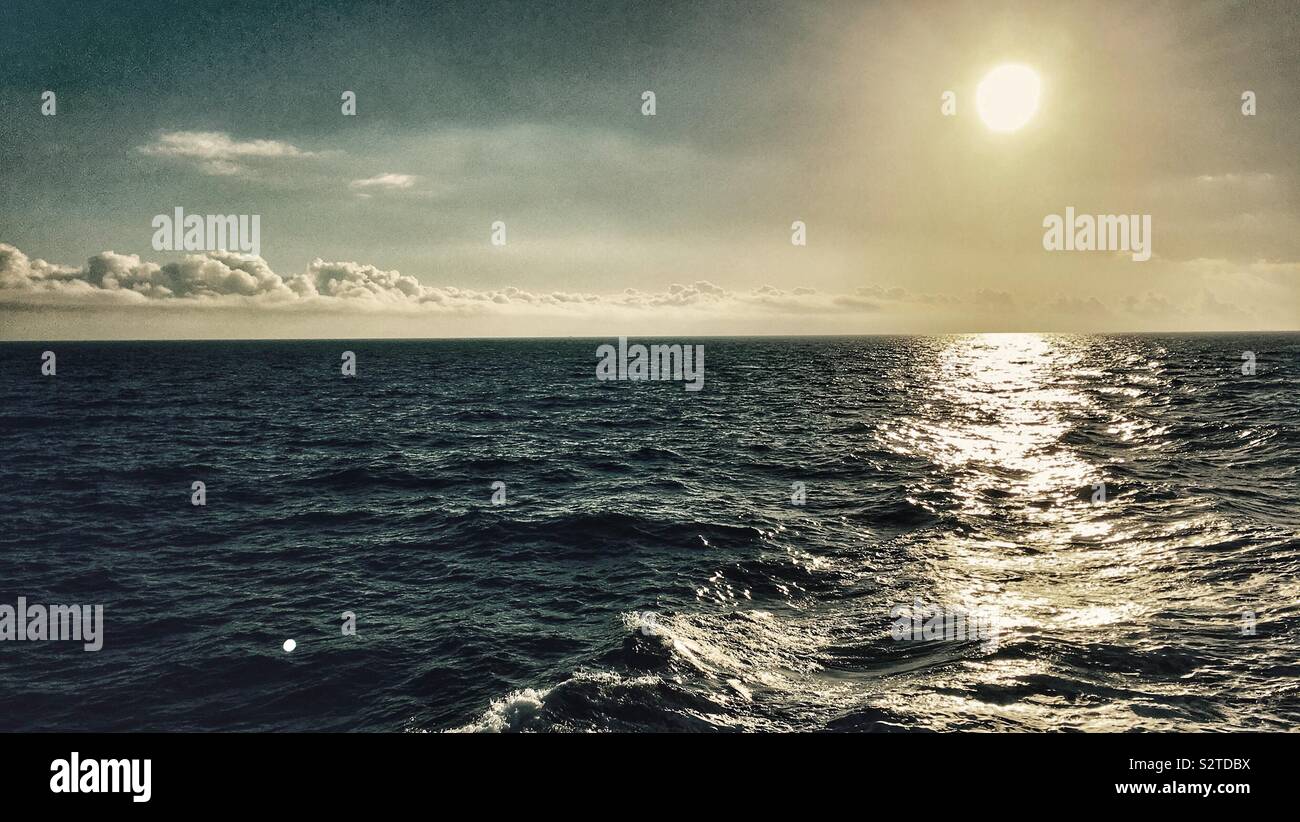 Low sun reflecting in sea Stock Photo