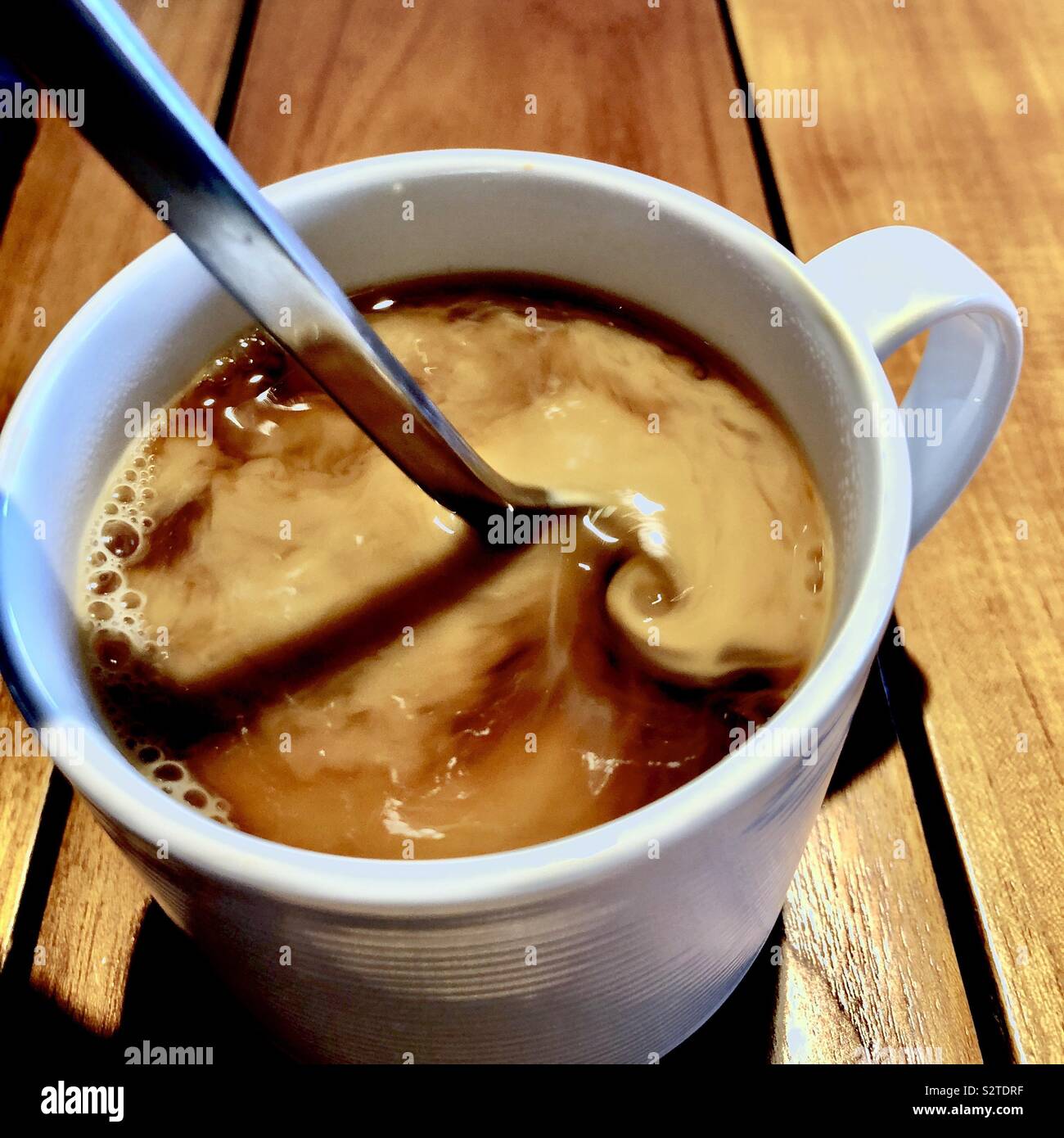 Cream being stirred in coffee with a spoon Stock Photo Alamy