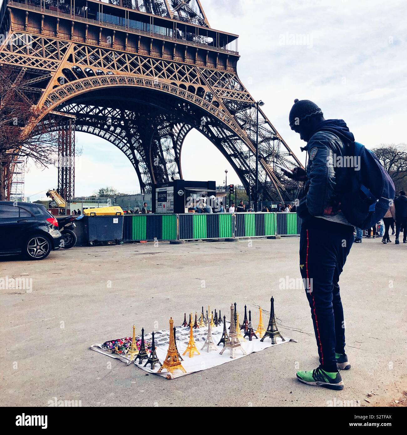 Souvenirs seller checking his phone at the foot of Eiffel Tower in Paris Stock Photo