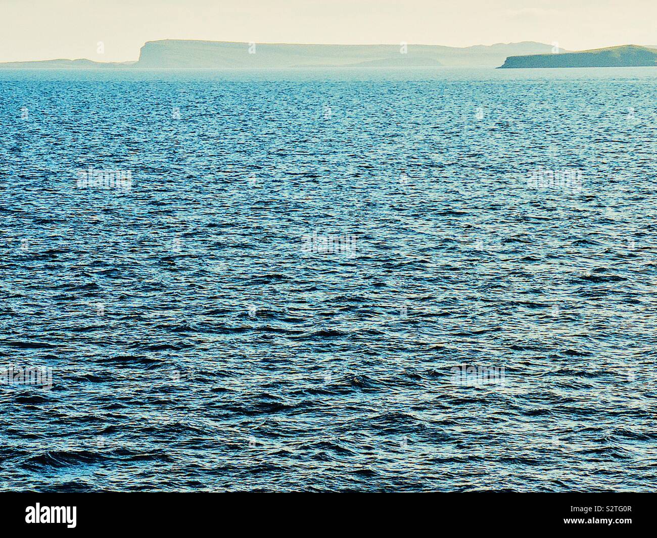 Minimalist view of deep blue sea with outline of islands on the horizon - Smartphone Captured Stock Image