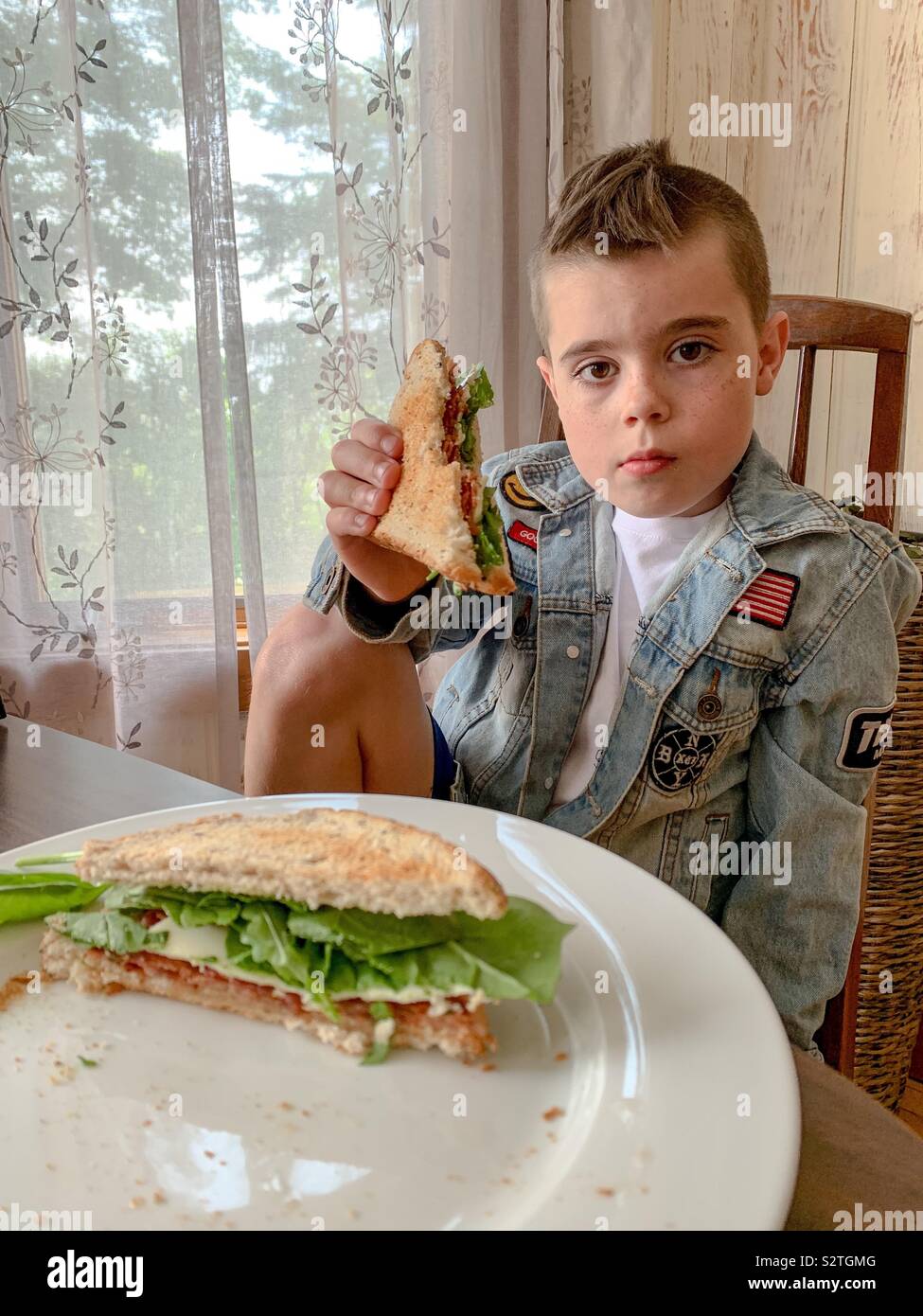 A nine year old boy eating a sandwich Stock Photo