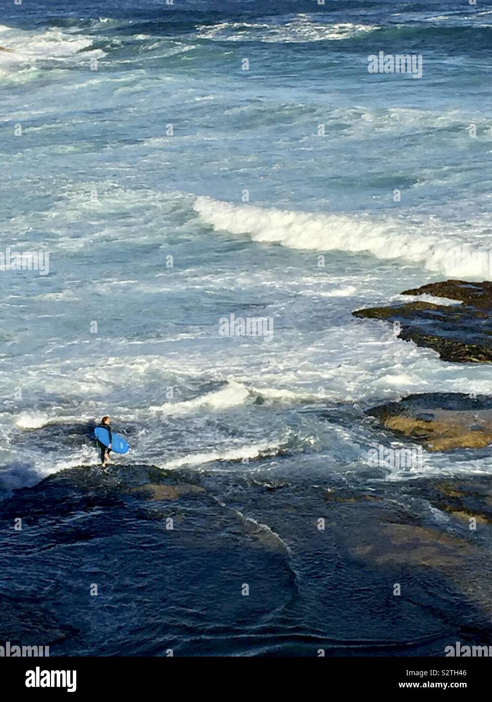 Surfer standing on a rock Stock Photo