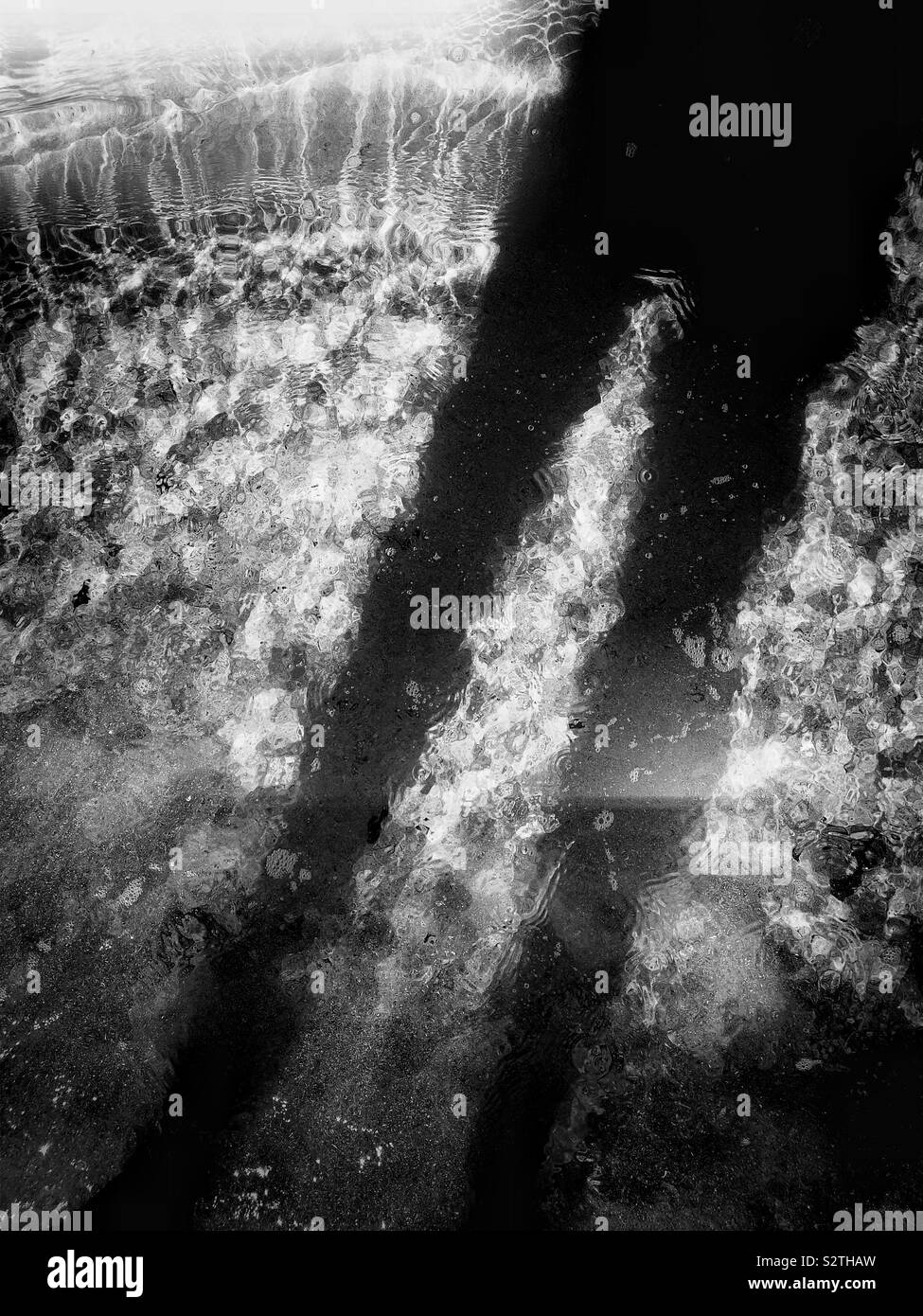 Dark shadow of man standing in clear sunlit rippled ocean - Smartphone Captured Stock Image