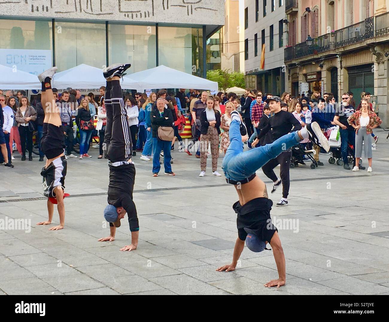 Three Street performers doing handstands during a dance performance in