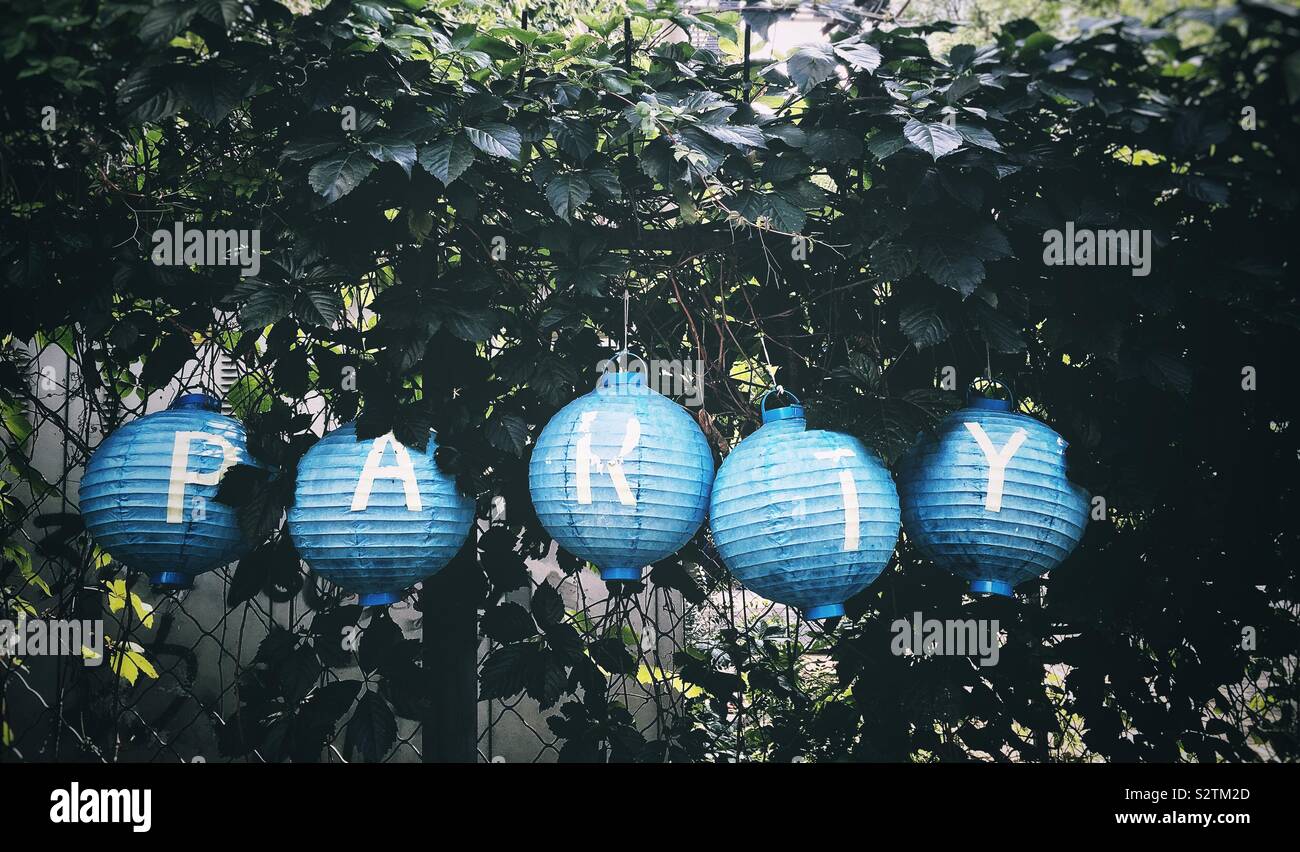 Party sign over a paper lanterns against a fence with wild grape leaves - Smartphone Captured Stock Image