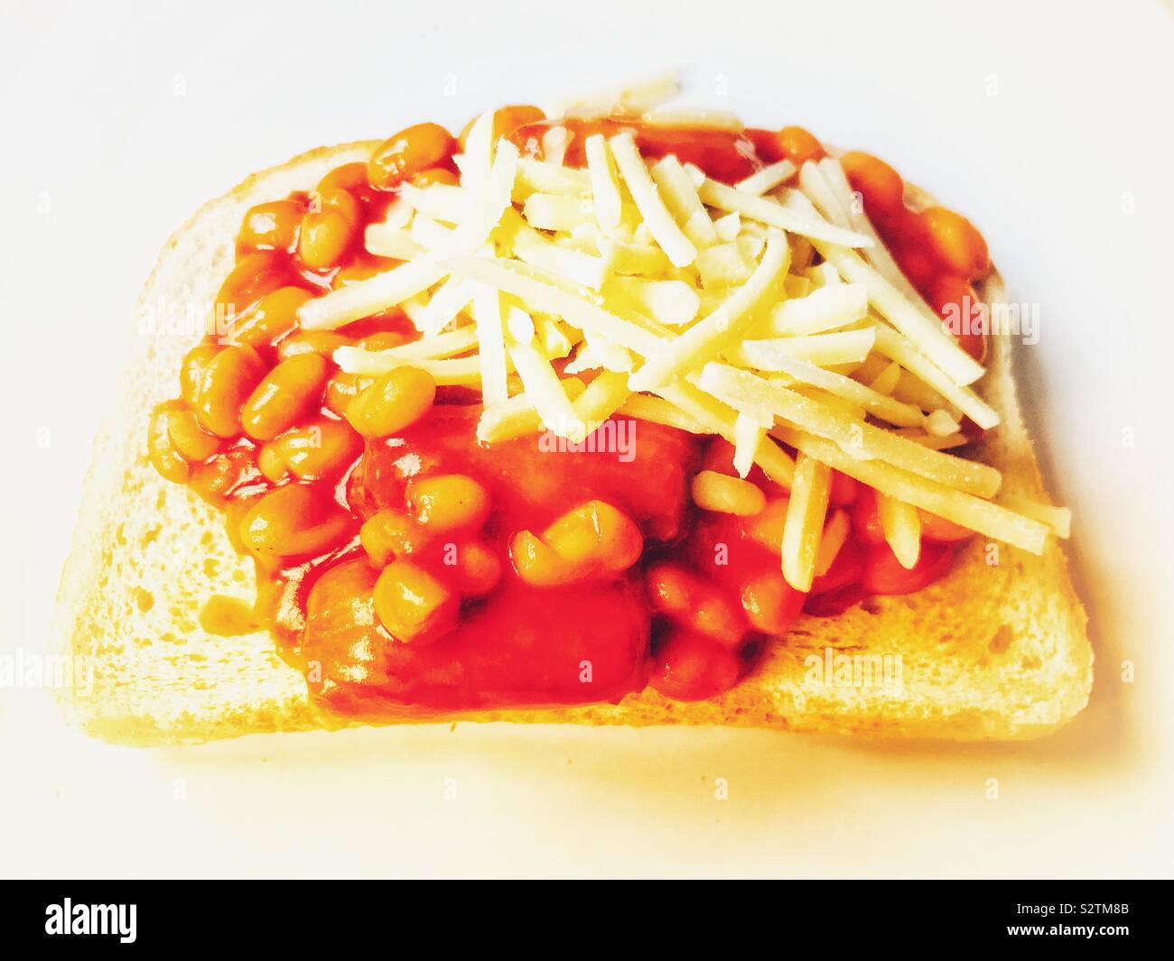 Baked beans and pork sausages served on white toast with grated cheese Stock Photo