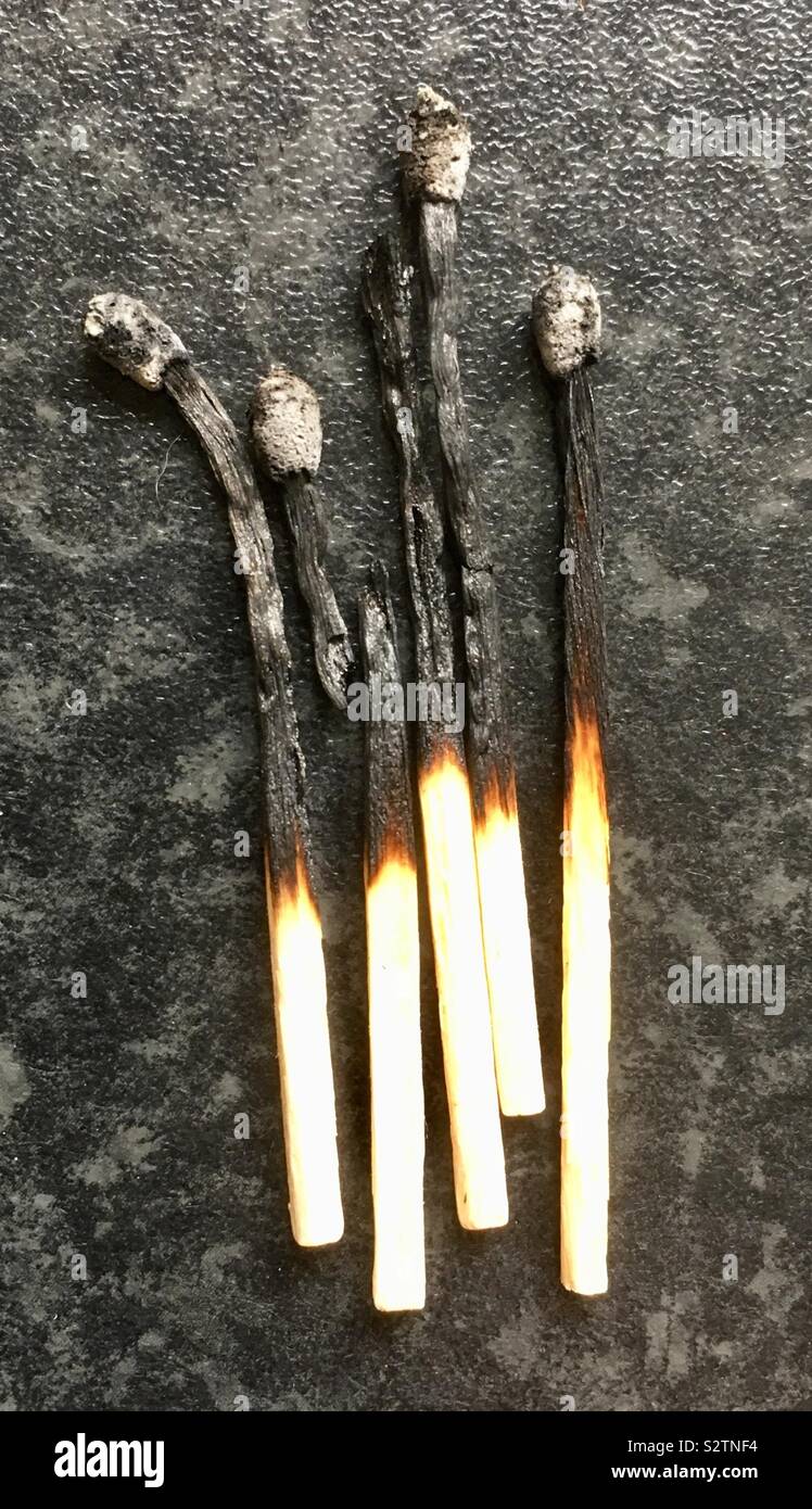 5 burnt matches on textured surface Stock Photo