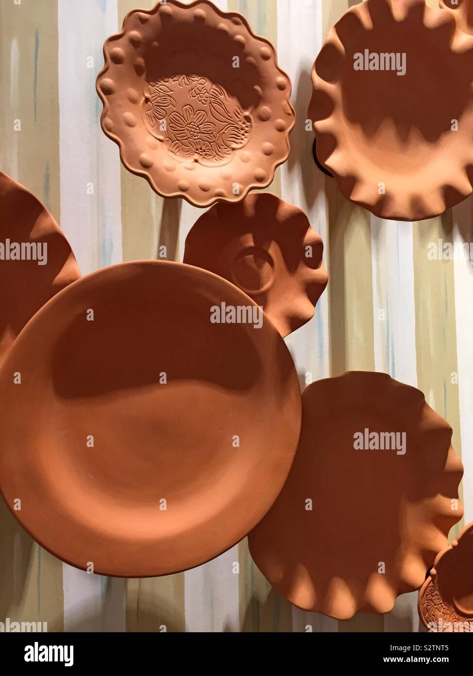 Display of pottery plates hanging from a wall in a retail store display, USA - Smartphone Captured Stock Image