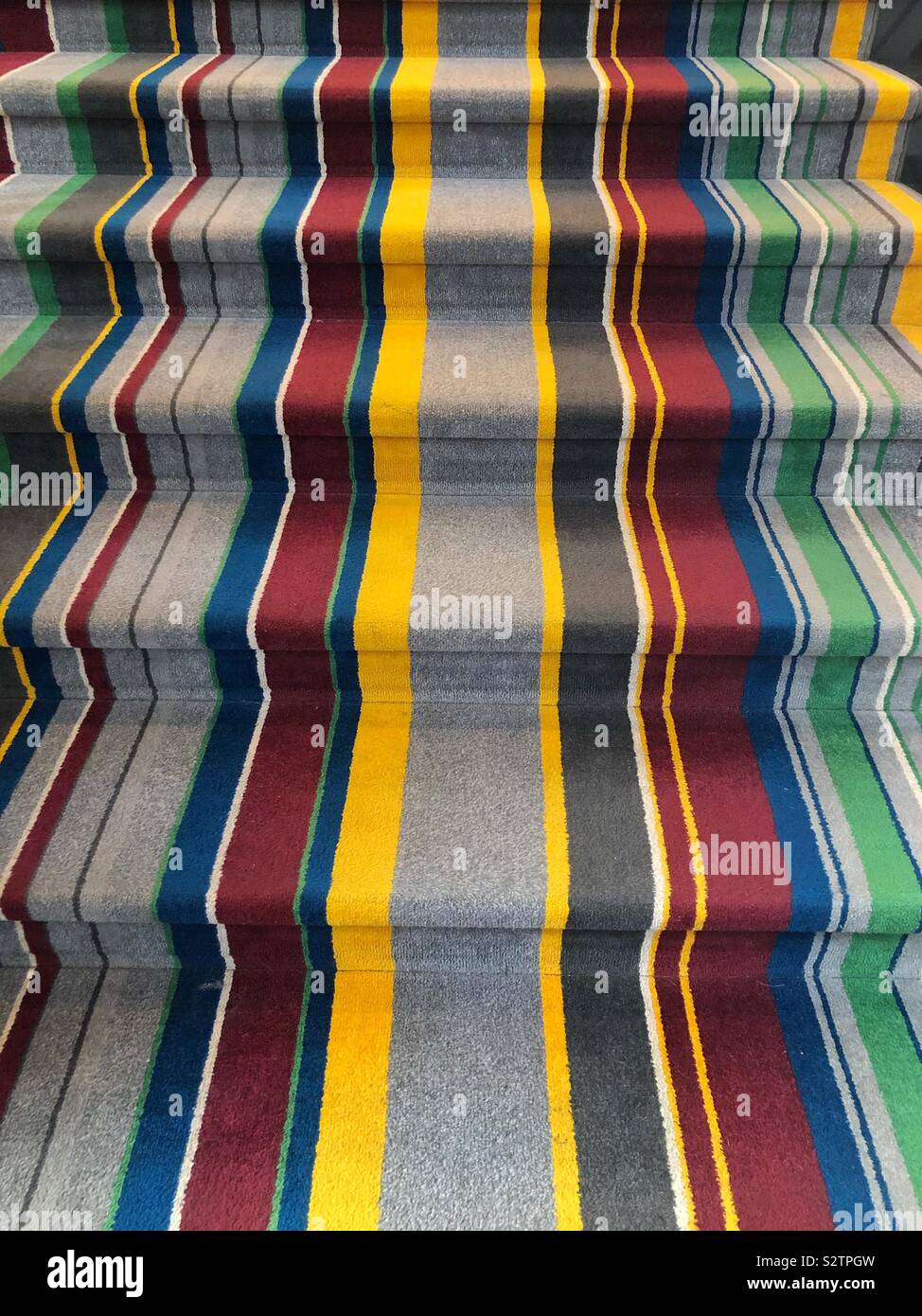A stairway covered in a colorful striped carpet Stock Photo