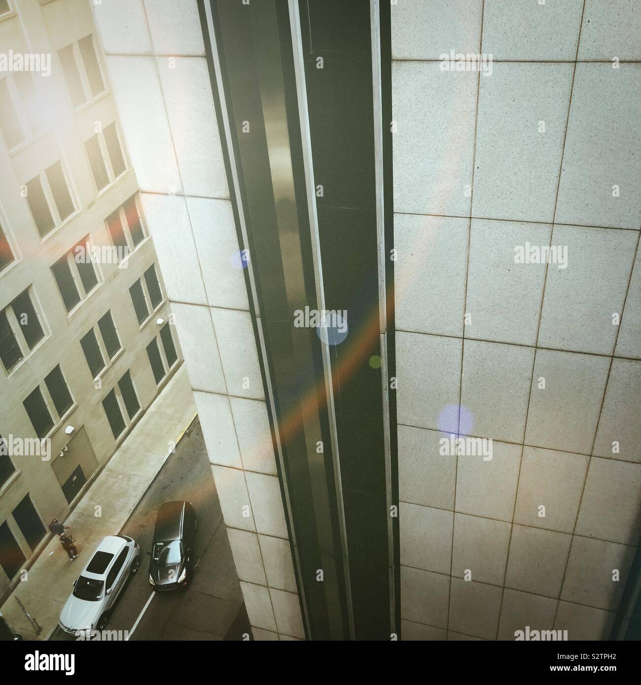 A view of two cars on a city street between large buildings - Smartphone Captured Stock Image