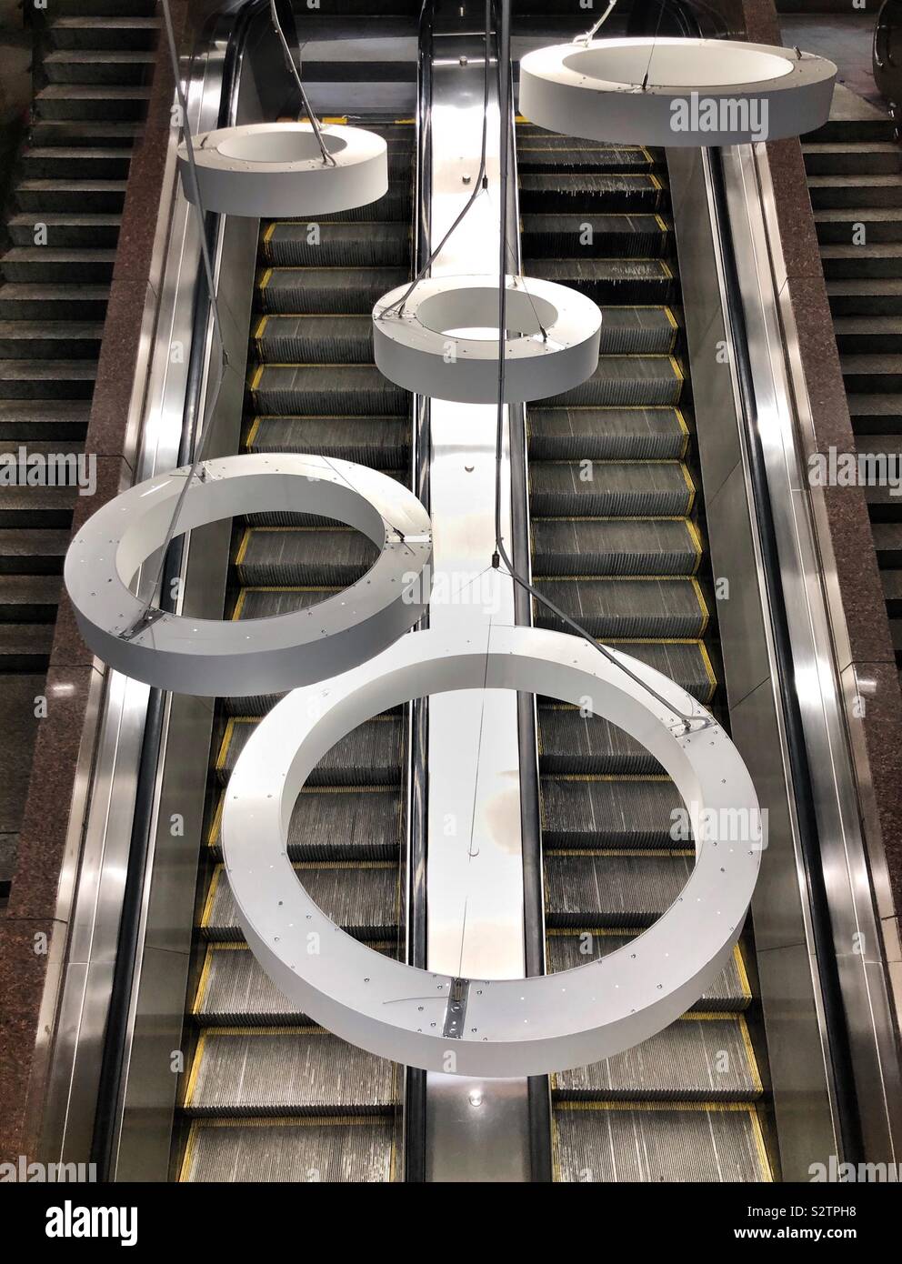 Round white circles hung as artwork over escalators in a subway station in downtown Pittsburgh Pennsylvania USA - Smartphone Captured Stock Image