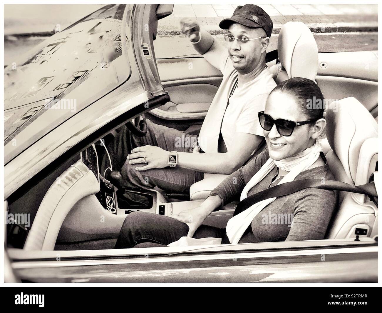 A young couple in a convertible sports car. - Smartphone Captured Stock Image