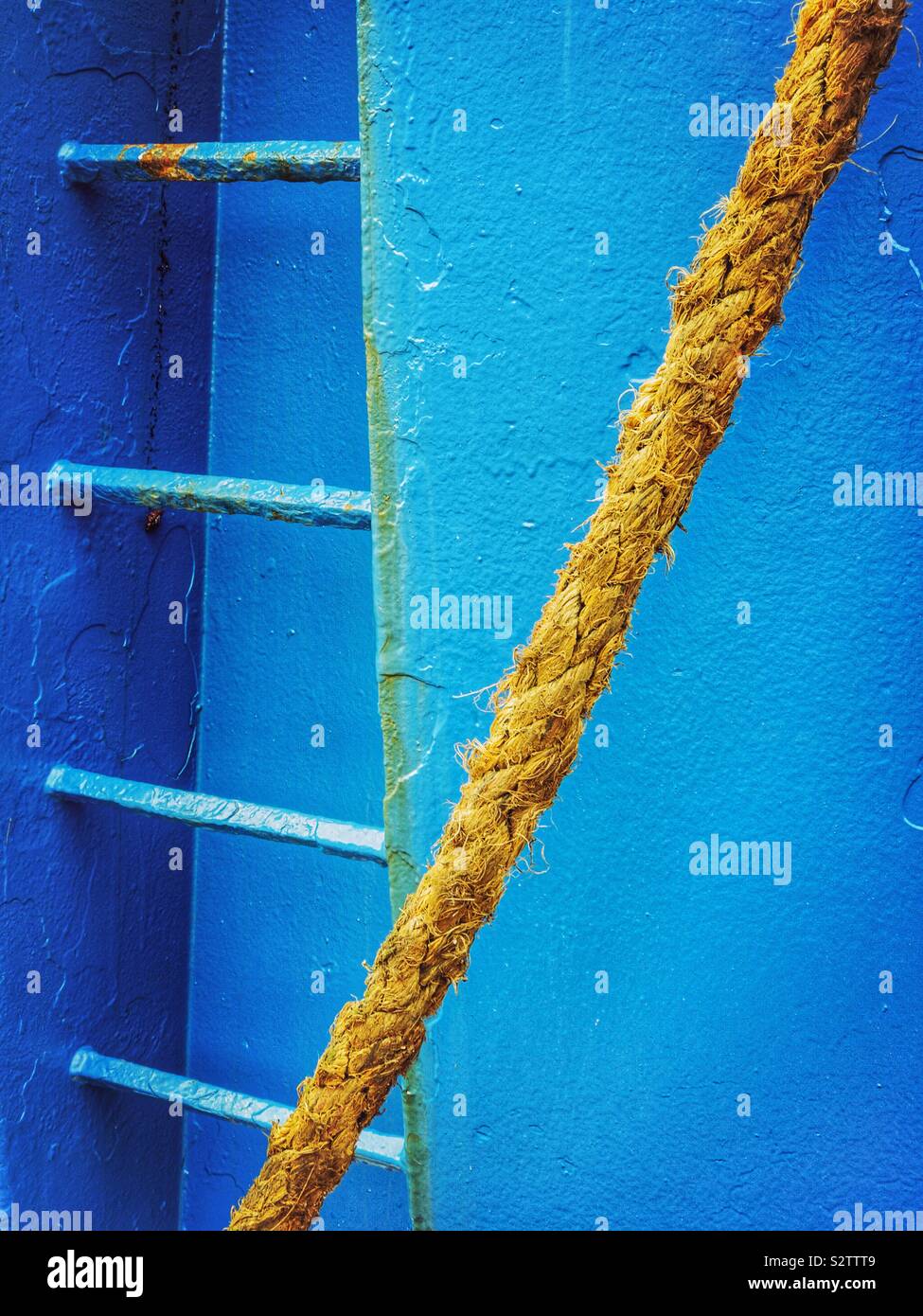 Detail of side of a blue ship with ladder and mooring rope. Stock Photo