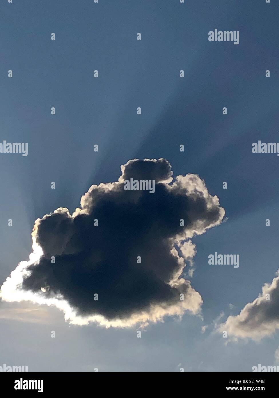 Darkened cloud hiding the sun against a blue sky Stock Photo