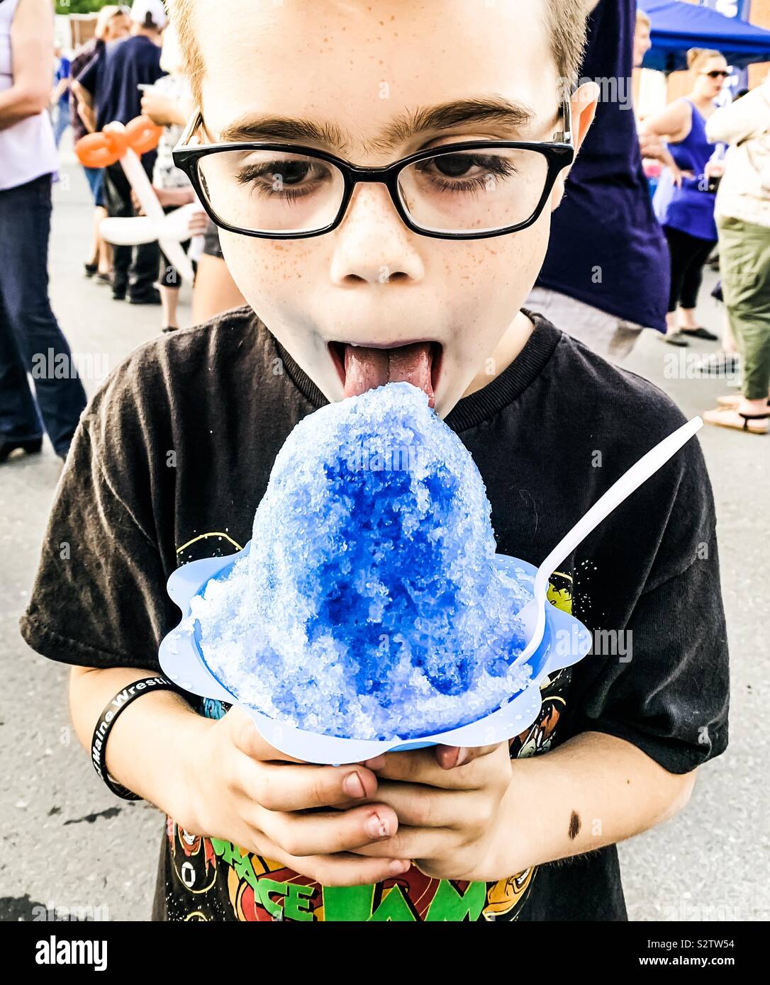 A nine year old boy enjoys a blue snow cone at a community summer event . Stock Photo