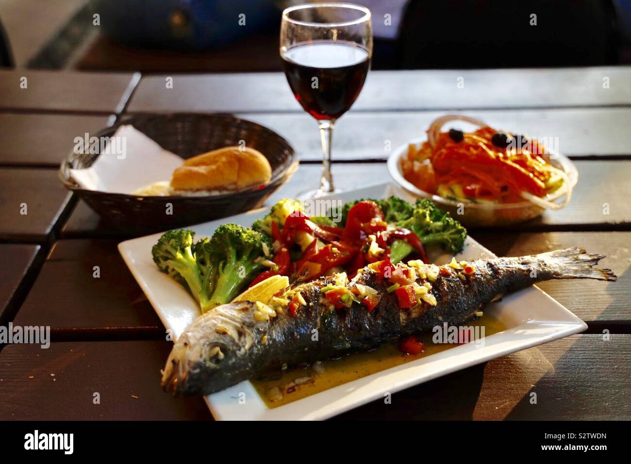 Sea bass fish dinner with red wine on a rustic wooden table Stock Photo -  Alamy