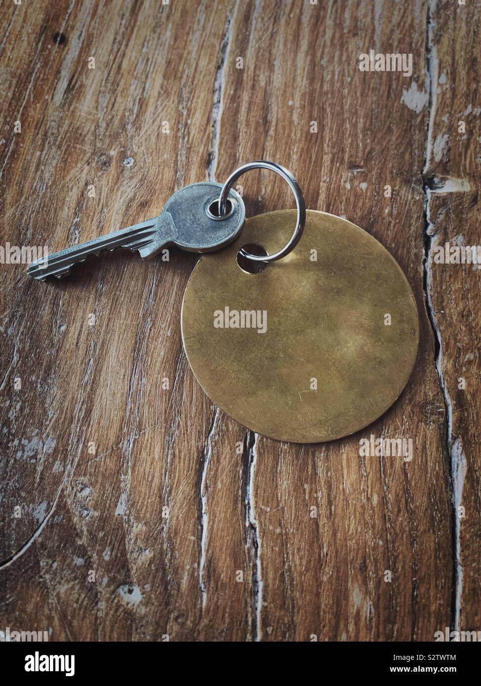 Key with blank tag or room number on a wooden table.  New home.  Property sale - Smartphone Captured Stock Image