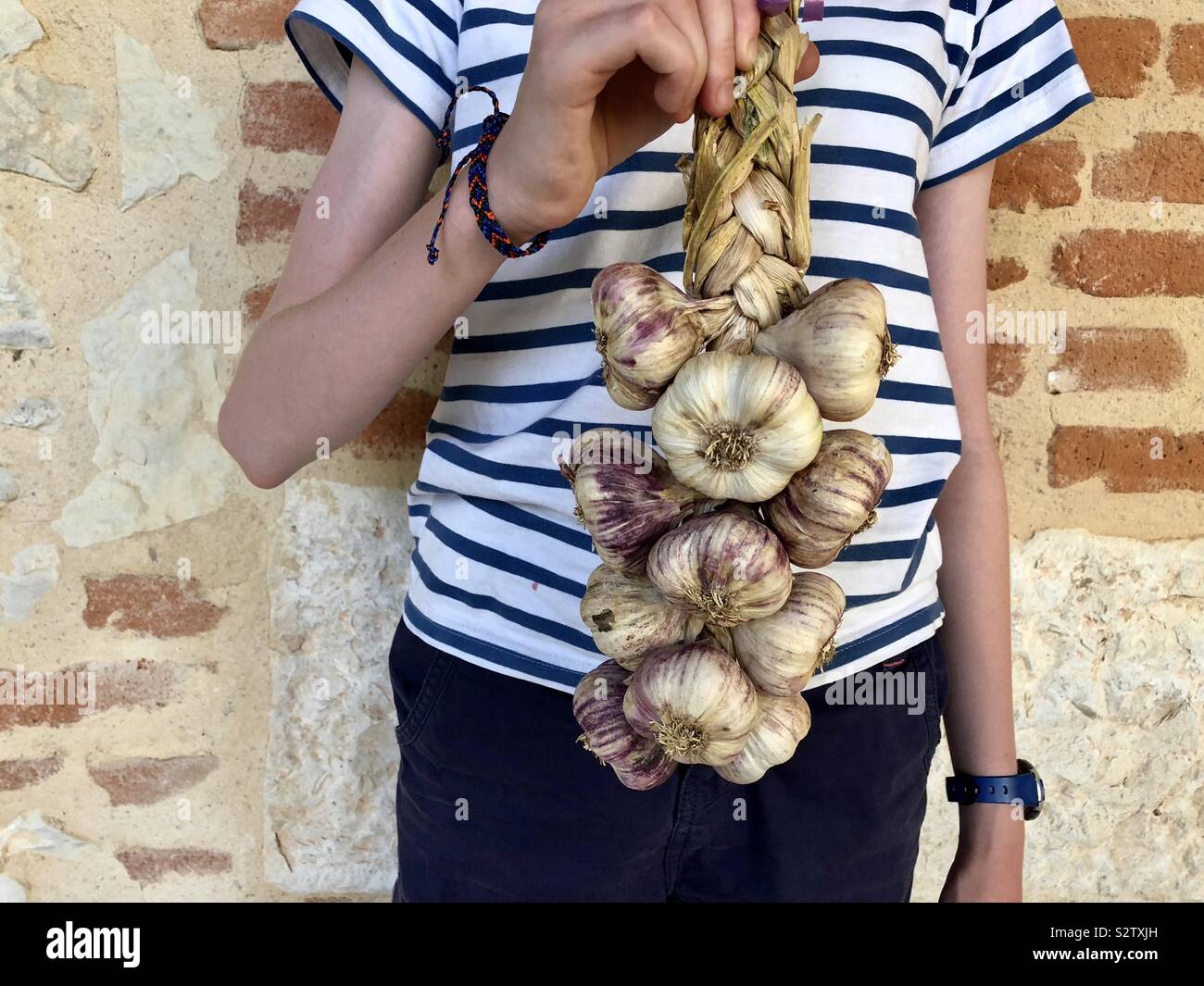 Girl in French T-shirt holding bunch of garlic - Smartphone Captured Stock Image