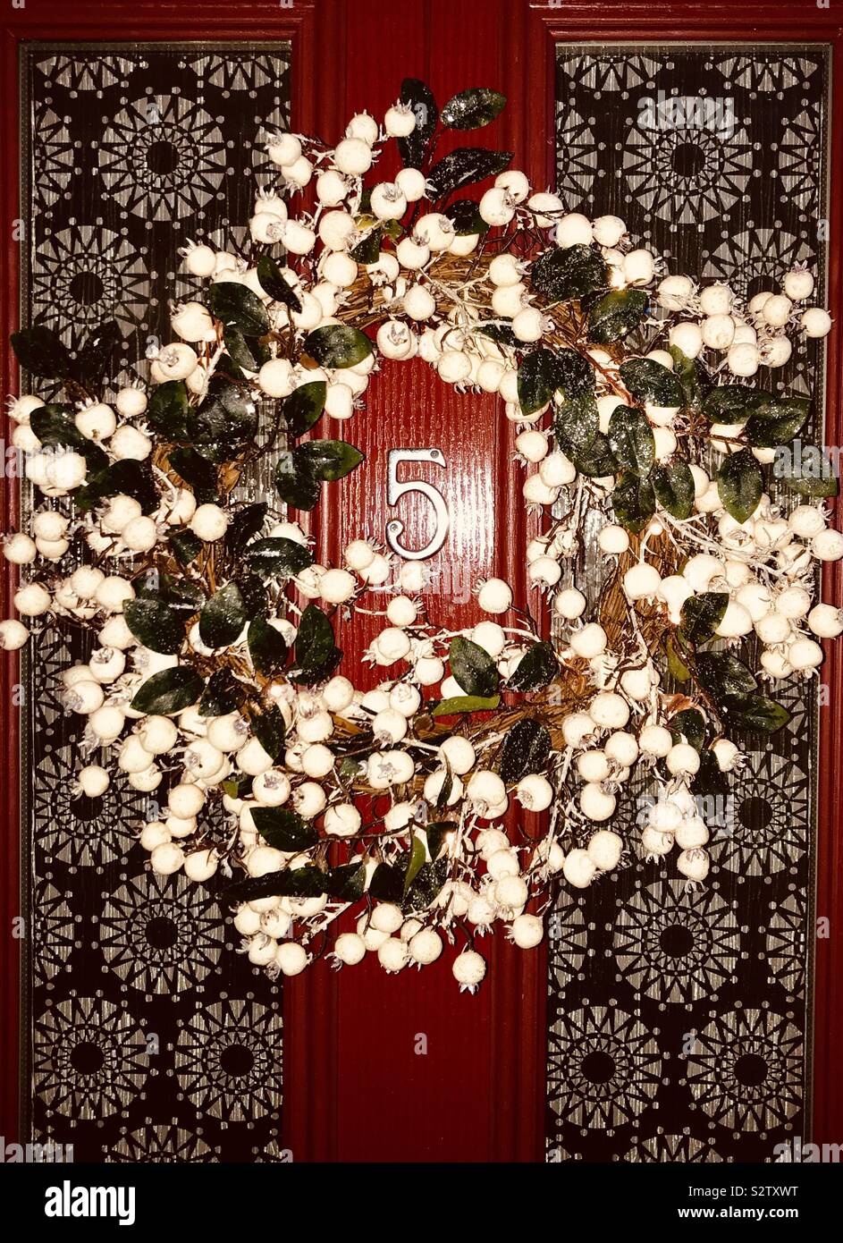 Berry wreath on red front door Stock Photo