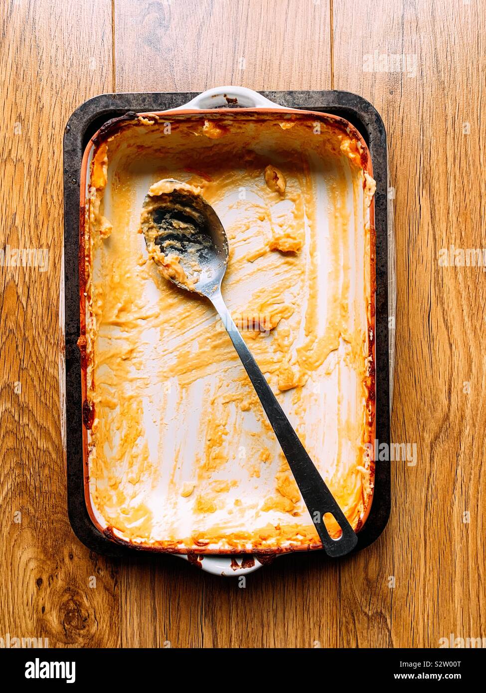 Empty casserole dish after a family meal with a metal spoon Stock Photo