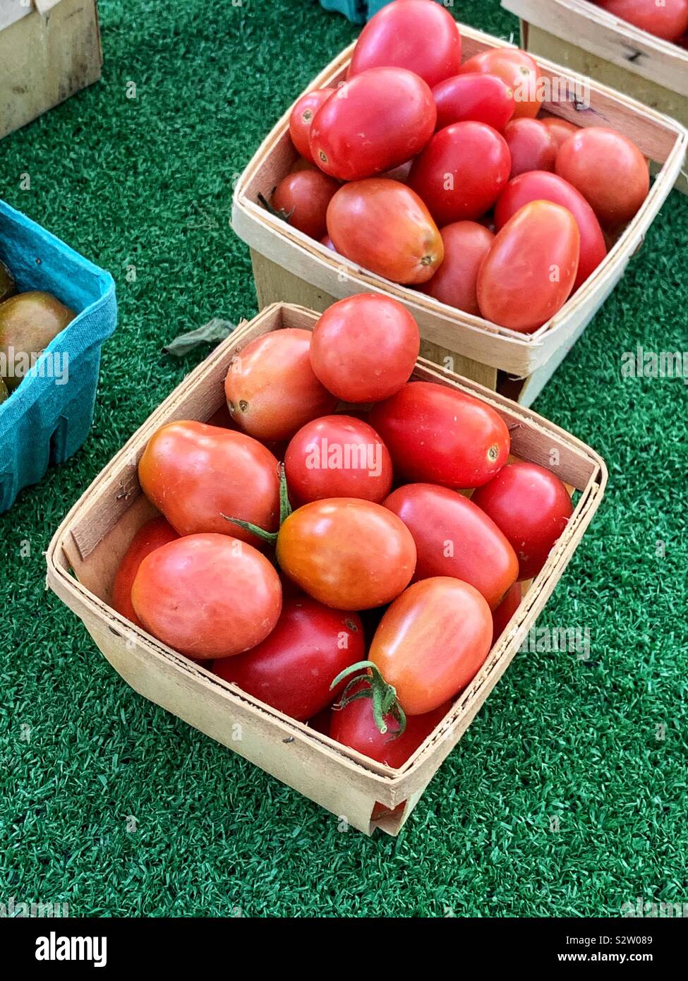 Farm fresh small red ripe tomatoes in wooden berry baskets at the farmers market. Stock Photo