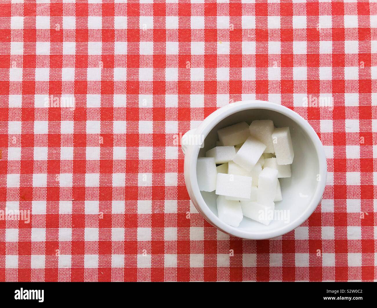 Bowl of sugar lumps on red and white background Stock Photo