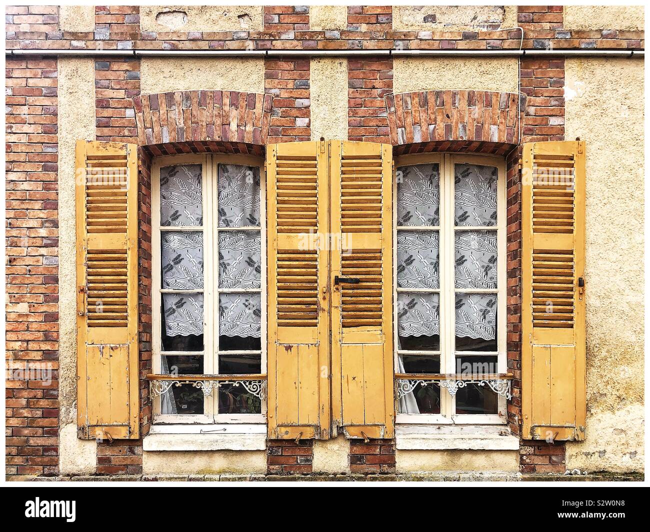 Traditional French windows with yellow shutters Stock Photo
