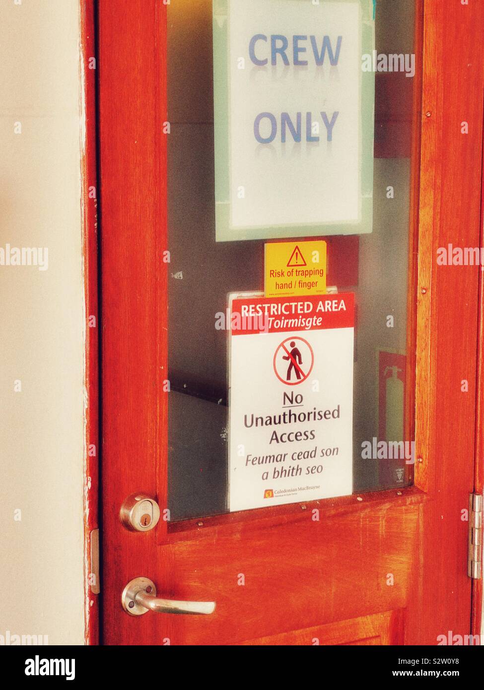 Signs on ferry door in English and Gaelic on a Caledonian MacBrayne ferry, Hebrides, Scotland - Smartphone Captured Stock Image