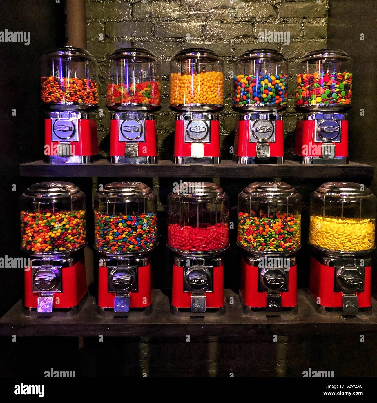 A large group of gumball machines filled with different types of candy Stock Photo