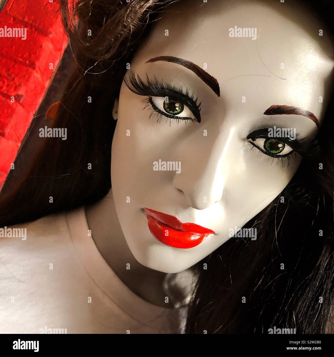 A closeup of a dark haired mannequin who has bright red lips Stock Photo