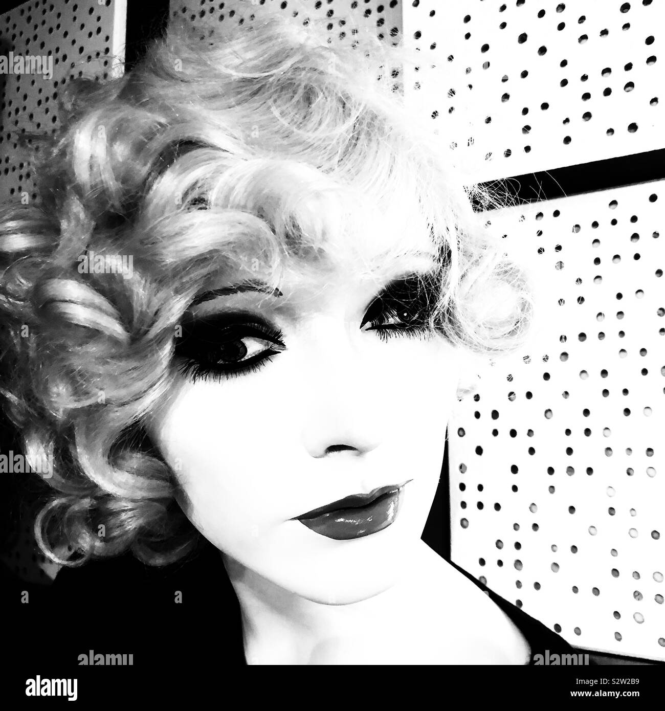 A back and white high key closeup of a female mannequin with blonde curly hair - Smartphone Captured Stock Image