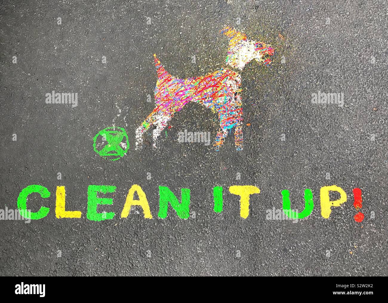 “Clean it up” message and graphic illustration on the tarmac footpath reminds dog owners that they are responsible for cleaning up after their dogs have downloaded waste products in Beddington Park. Stock Photo