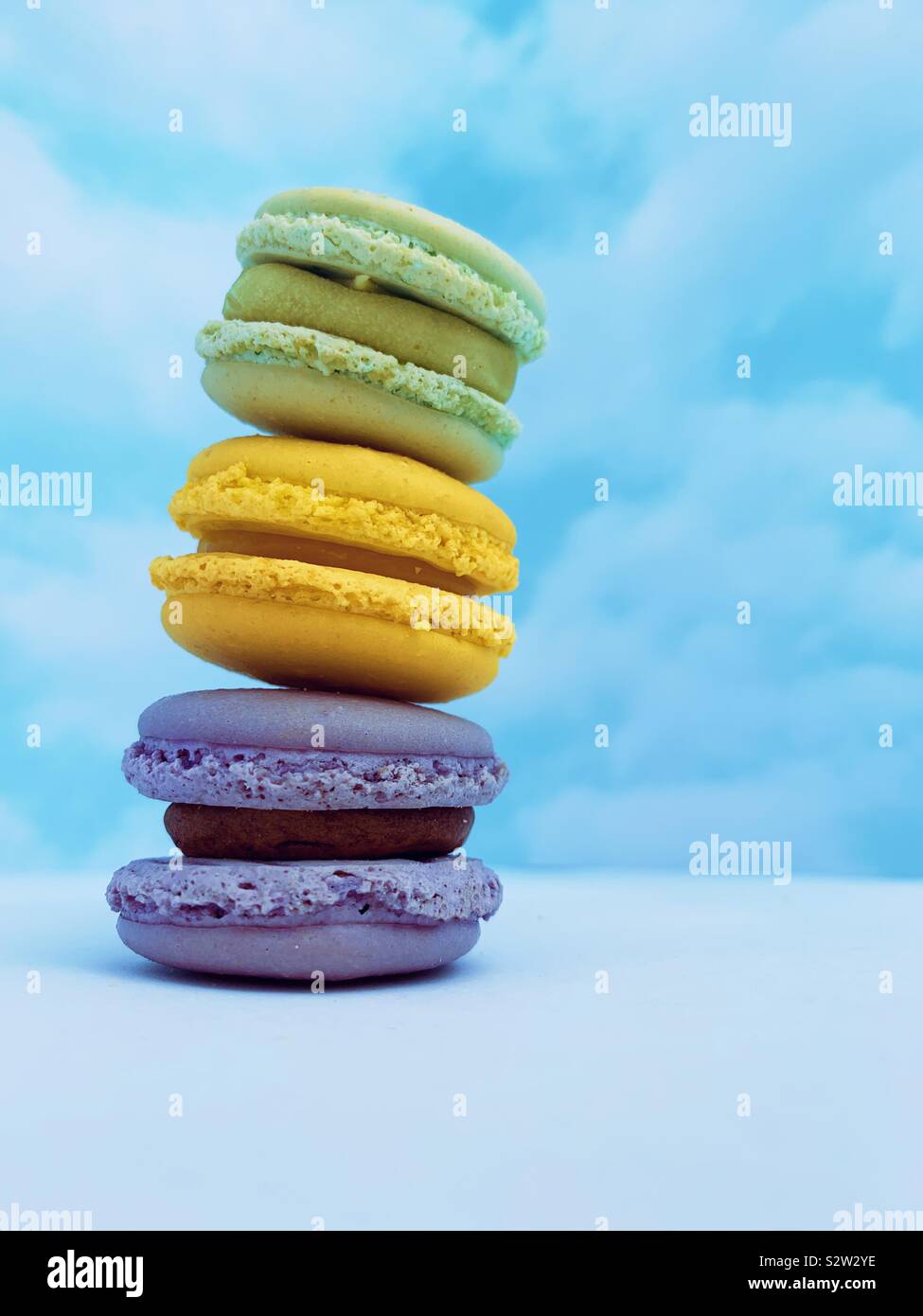 Three colourful macarons placed one on top of other with sky background. Stock Photo
