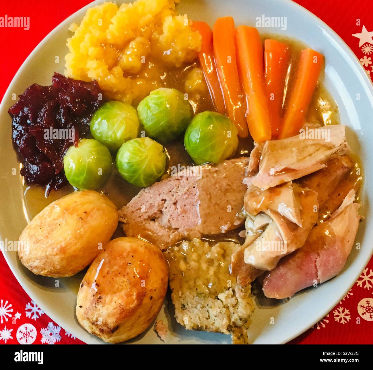 Christmas roast turkey dinner served in a pale plate with a red place mat Stock Photo