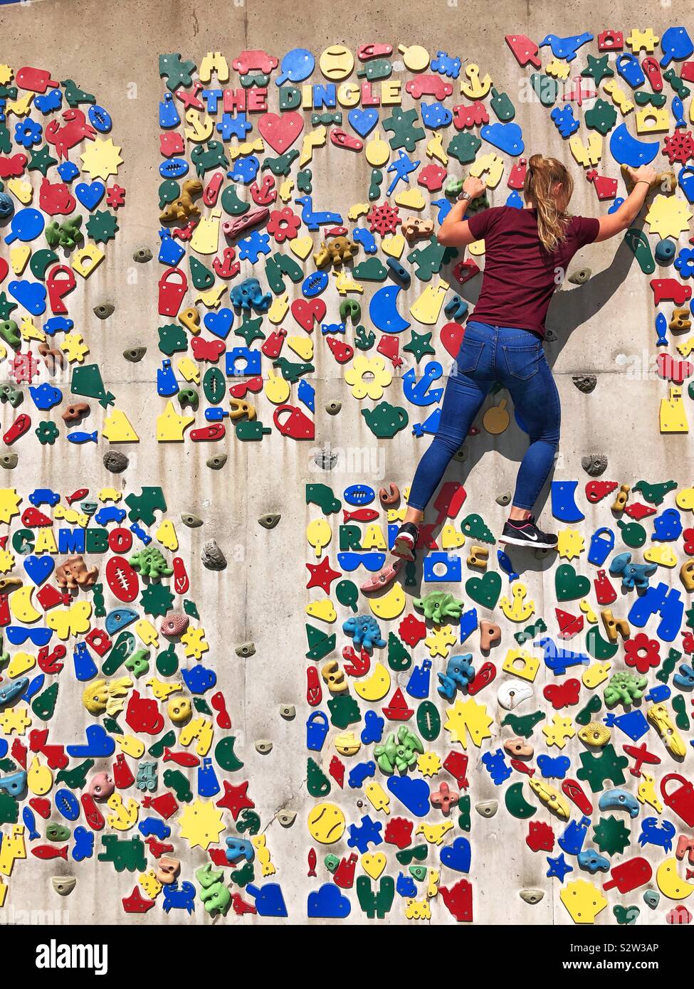 Young woman enjoying climbing the public climbing wall at Barry Island, South Wales, August. - Smartphone Captured Stock Image