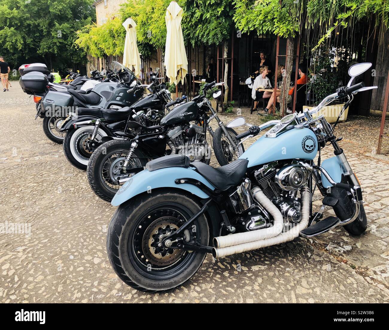 Row seat f Harley Davidson motorcycles parked outside a restaurant in a French town Stock Photo