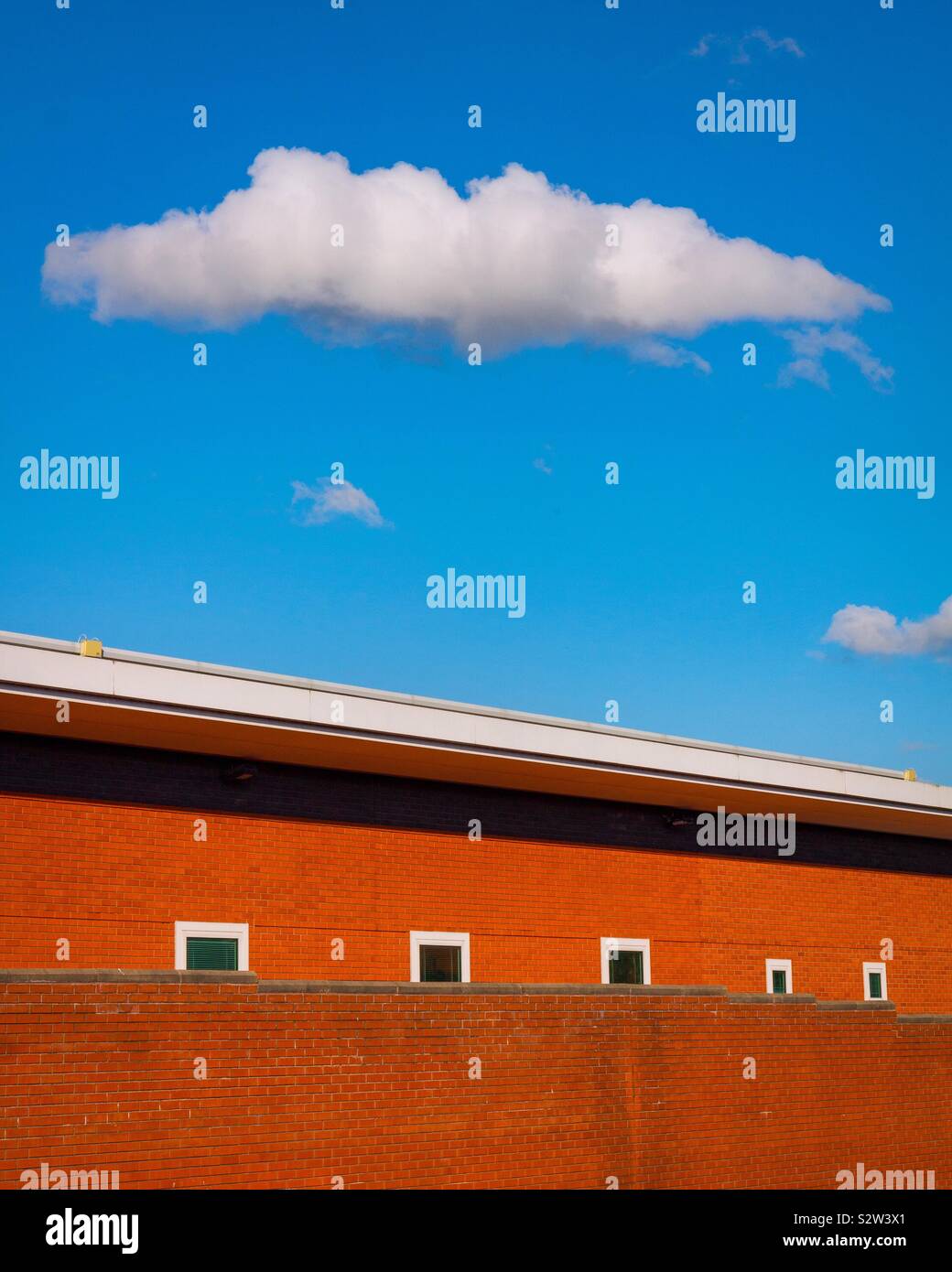 Modern building with white cloud above surrounded by blue sky - Smartphone Captured Stock Image