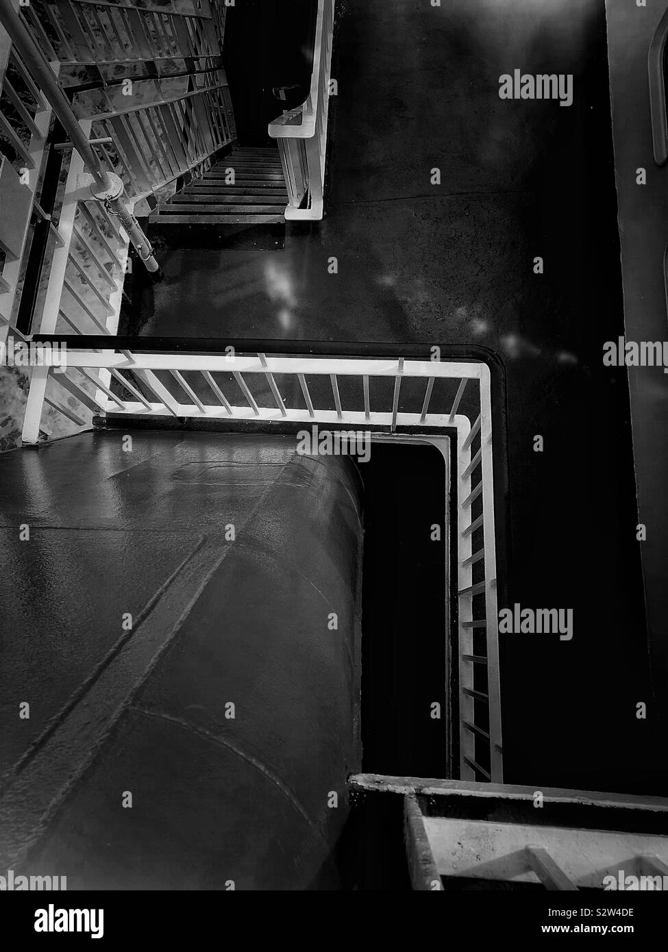 Atmospheric black and white image of stairway between decks on ship - Smartphone Captured Stock Image