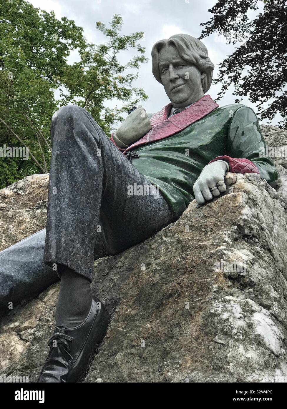 Dublin, Ireland - June 7, 2019: Oscar Wilde is depicted as a sculpture atop a boulder in Merrion Square. The statue, by Danny Osborne, is composed of a variety of stones and was unveiled in 1997. - Smartphone Captured Stock Image