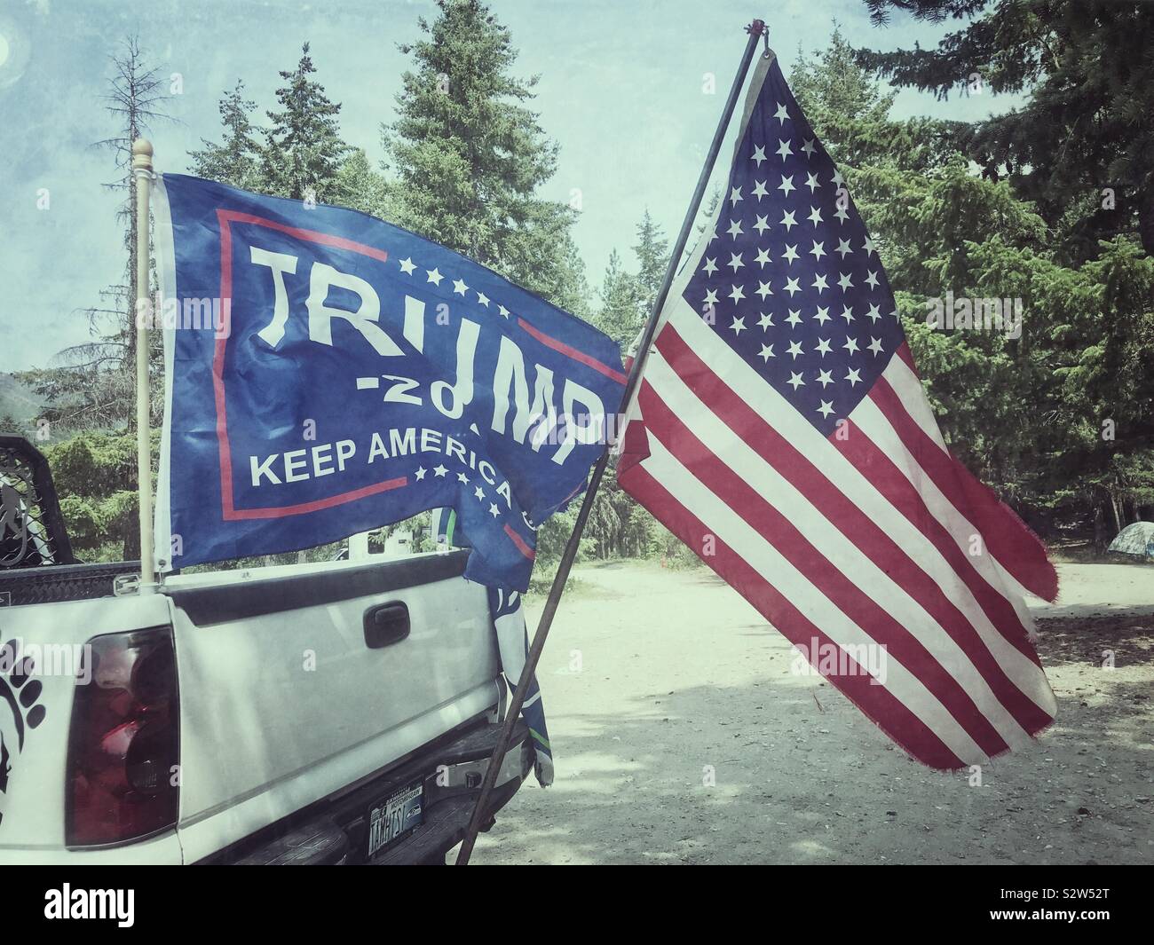 USA flag and Trump campaign flag fly from back of white pickup on July 4 - Smartphone Captured Stock Image