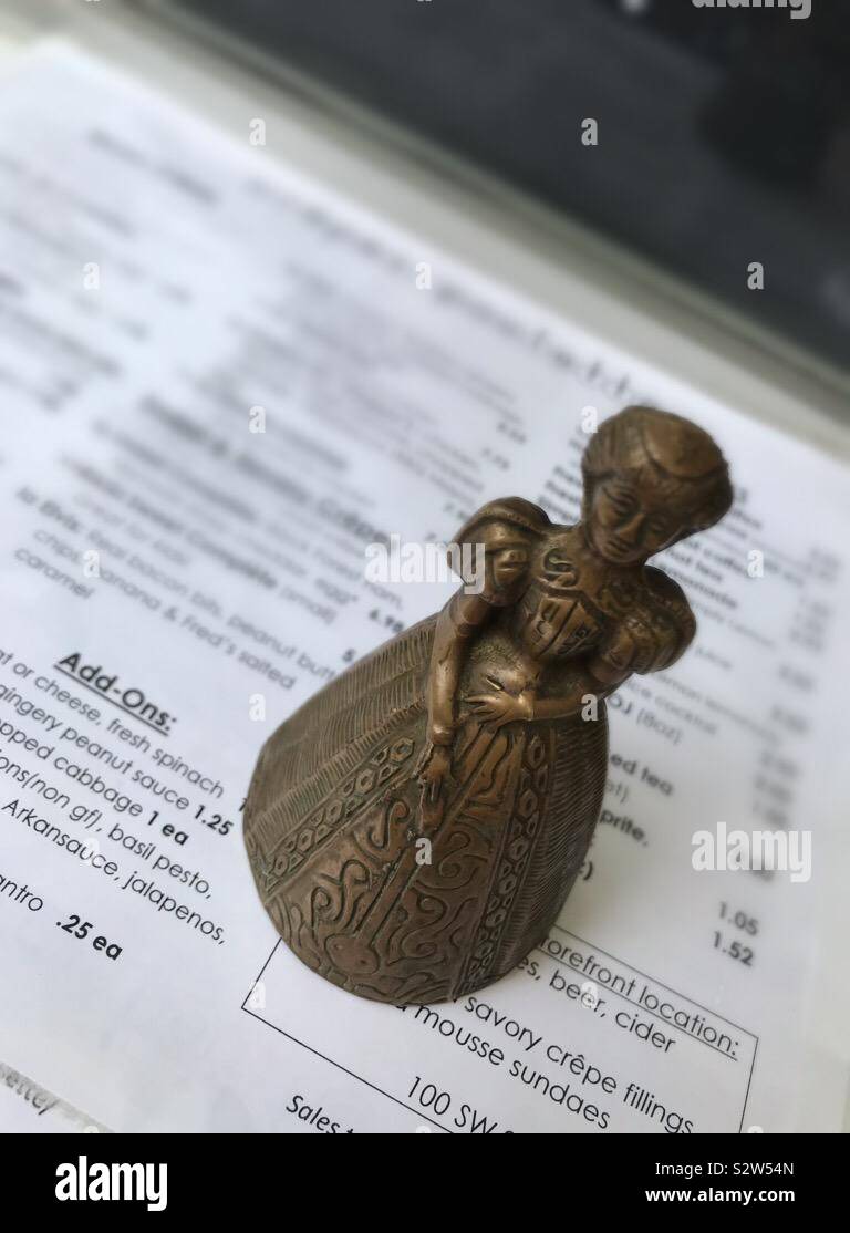 A sculpted bell holding down a menu at a food truck. - Smartphone Captured Stock Image