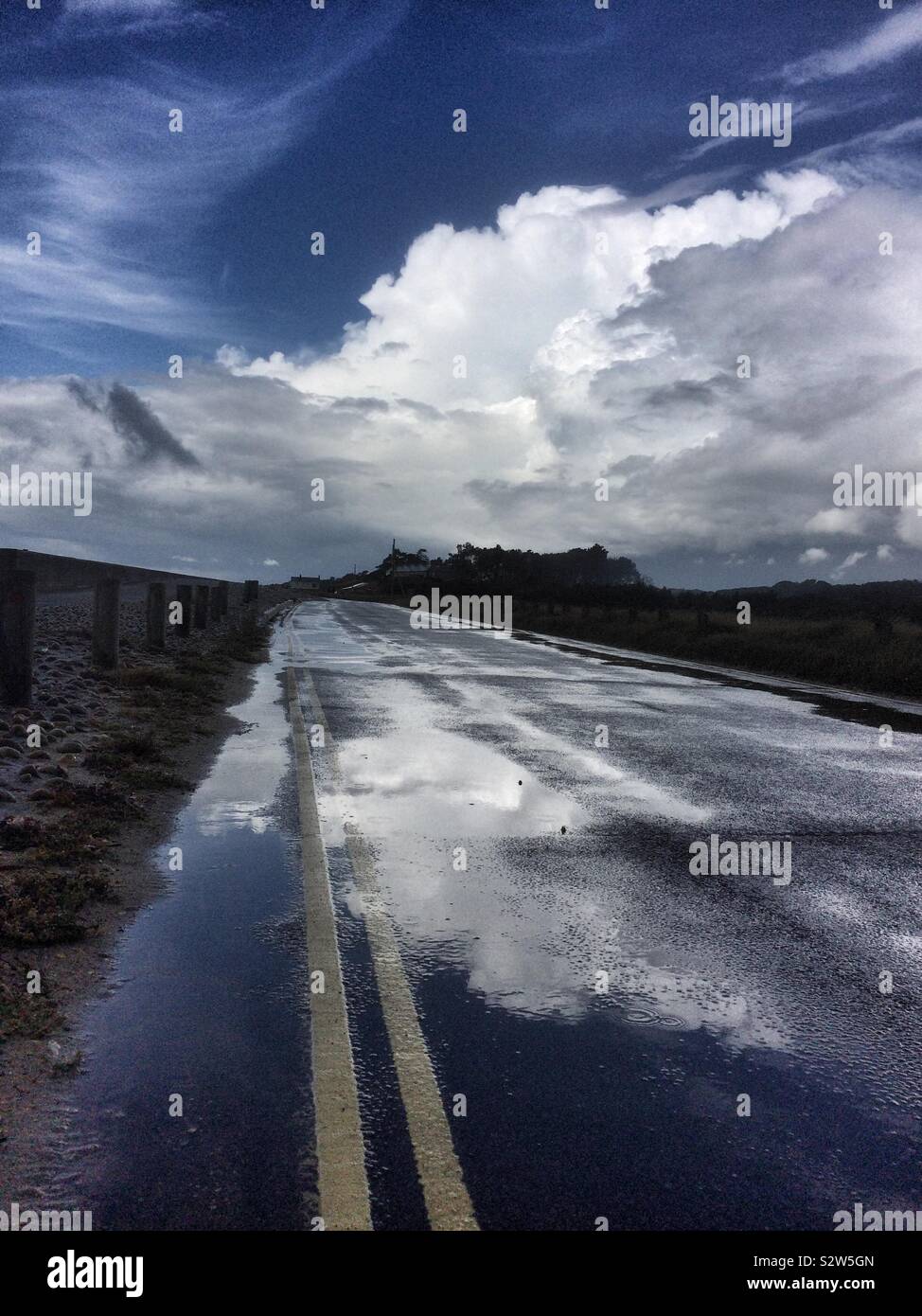 Yellow lines and road with water at Lepe beach,south UK,Hampshire,with cloudy sky - Smartphone Captured Stock Image