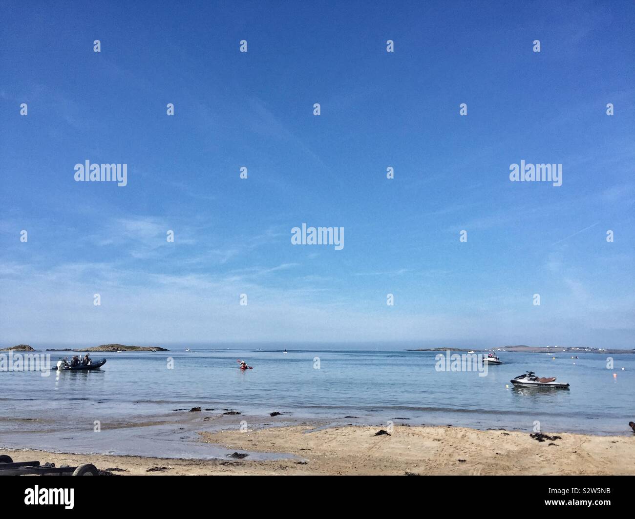 Boats on the water at high tide on a calm day in Rhosneigr, Traeth Crigyll, Anglesey, North Wales - Smartphone Captured Stock Image