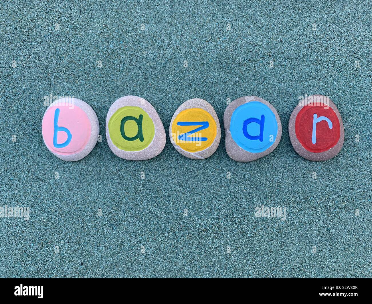 Bazar word composed with colored stone letters over green sand - Smartphone Captured Stock Image