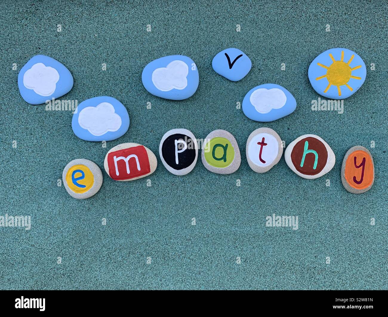 Empathy word composed with handmade carved and colored letters over green sand - Smartphone Captured Stock Image