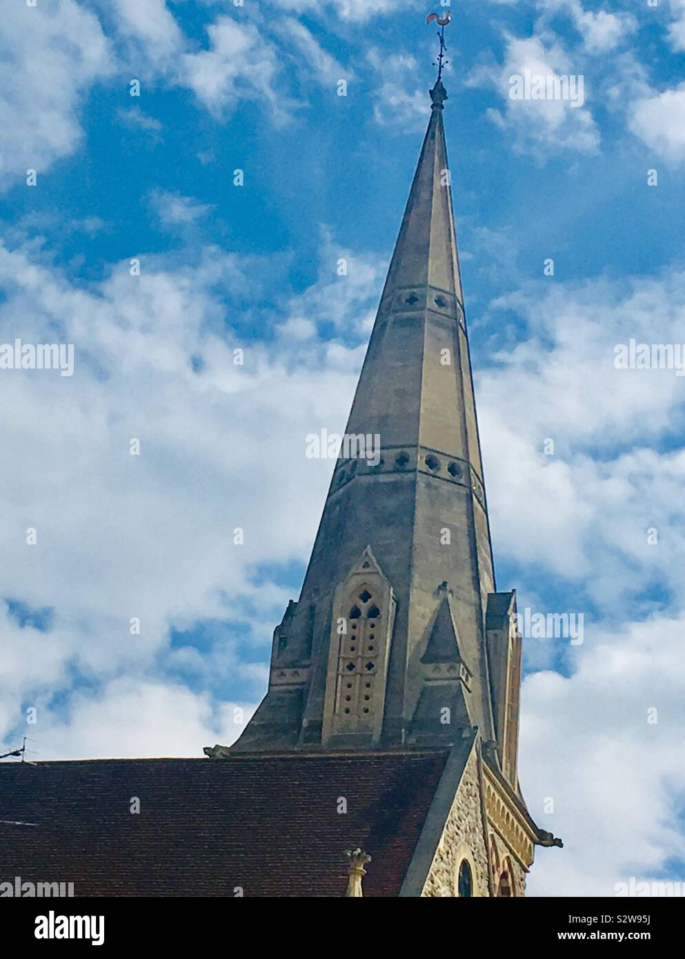 Close up view of vertical church spire and building against a backdrop of bright blue sky with clouds - Sacred Heart Polish and Romanian Catholic Church, Watlington Street, Reading, United Kingdom Stock Photo