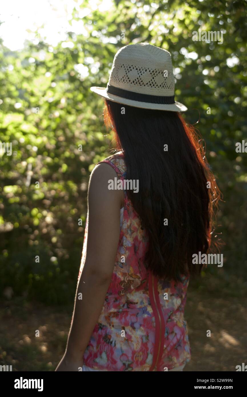 pretty girl in hat stands back to camera looking at sun - Smartphone Captured Stock Image