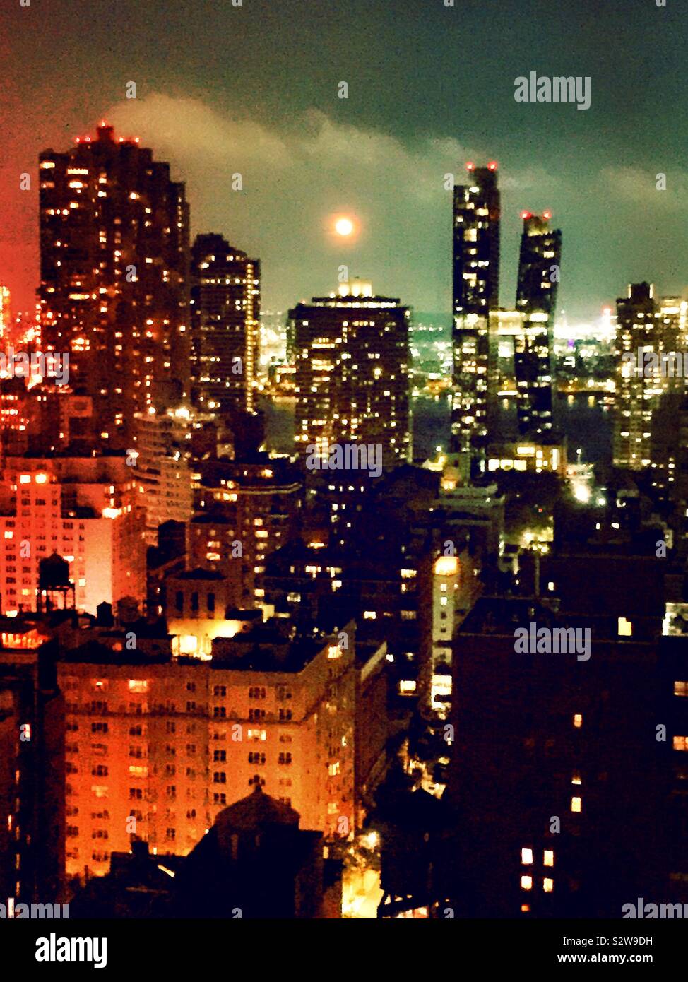 Full moon rising over the East River as seen from a roof deck in midtown Manhattan neighborhood of Murray Hill, NYC, USA - Smartphone Captured Stock Image