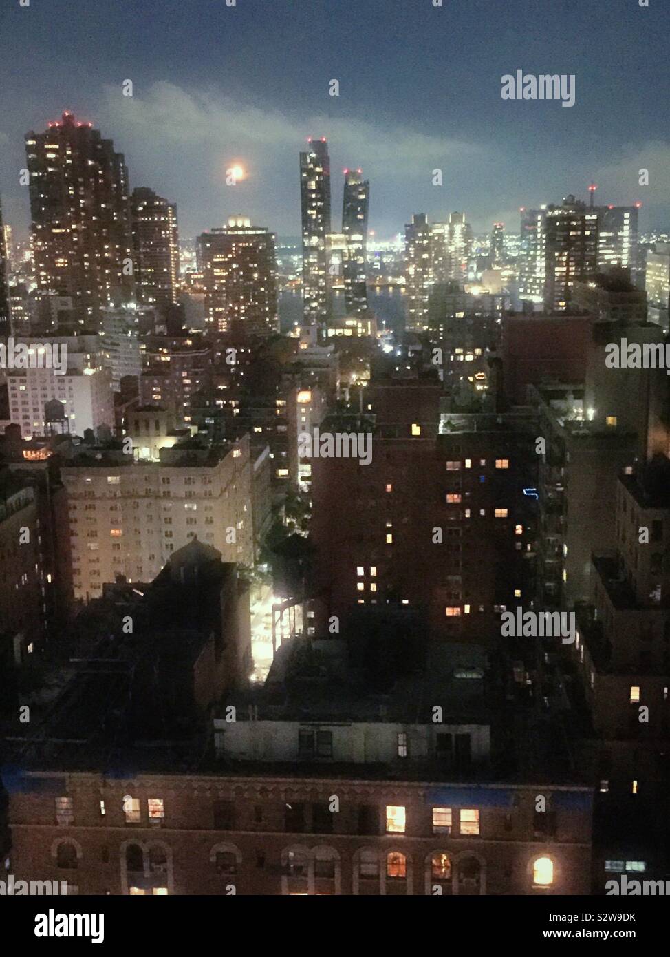 Full moon rising over the east river as seen from a roof deck in midtown Manhattan in the neighborhood of Murray Hill, NYC, USA - Smartphone Captured Stock Image